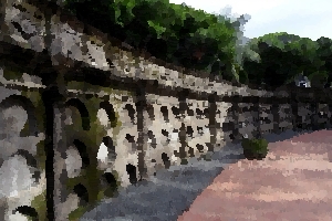 A moss-covered stone wall surrounding the Paco Park cemetery.