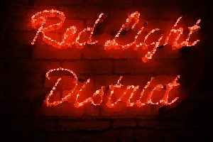 A Red Light District sign made of red neon on a brick wall.